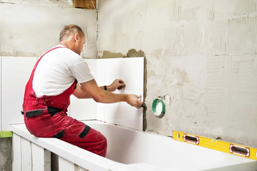 A professional from Builders Queenstown working on bathroom renovation Queenstown, installing tiles with precision.