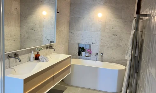 Contemporary bathroom with floating double vanity, stylish bathtub, and wood-accented ceiling by Bathroom renovations Queenstown.